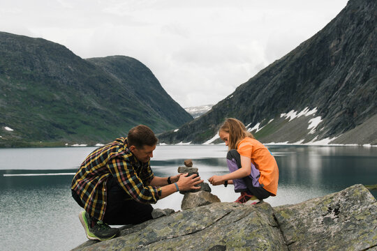 father and daughter building a rock tower in the mountains in Norway