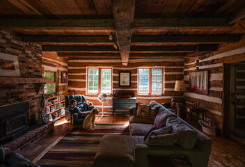 Boy and dog sitting in cozy log cabin cottage on sunny day.