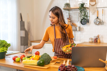 Portrait of beauty body slim healthy asian woman eating vegan food healthy with fresh vegetable salad in kitchen at home.diet, vegetarian, fruit, wellness, health, green food.Fitness and healthy food