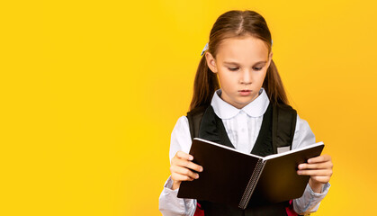 Schoolgirl holding books ready for Back To School standing in studio on yellow background. School Education Concept