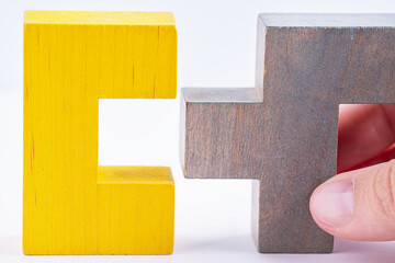 Hand holding wooden puzzle element. Hand sets the last element of the puzzle. The concept of logical thinking. Geometric shapes on a wooden background. Wooden blocks.