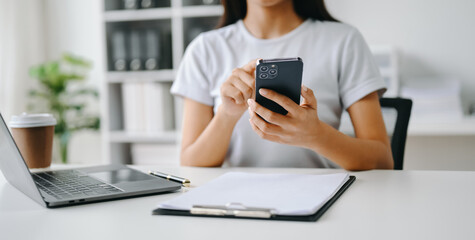 Fototapeta premium Asian Woman using smart phone for mobile payments online shopping, omni channel, sitting on table, virtual icons graphics interface screen .
