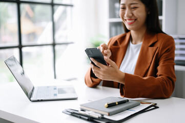 Young beautiful woman typing on tablet and laptop while sitting at the working white table modern office