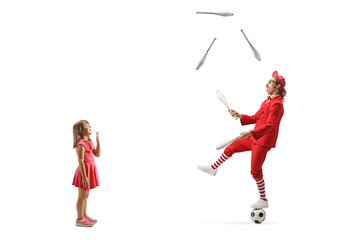 Surprised little girl looking at a man standing on a football and juggling