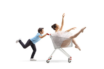 Boy pushing a ballerina inside a shopping cart - obrazy, fototapety, plakaty