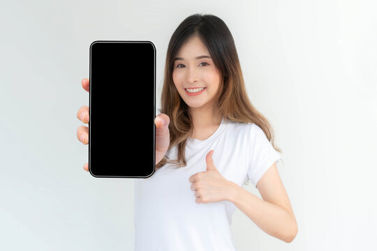 beautiful Asian young woman showing big smart phone with blank screen , black screen empty copy space for advertising banner isolated on white background , Mock Up Image