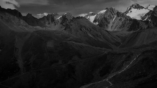 Stylised in an old archived style footage view of mountains with glaciers. 4K black and white video with noise and scratches effects.