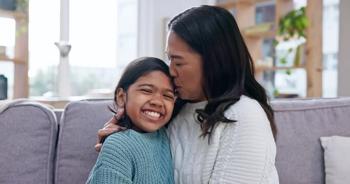 Family, face and mother kiss girl child on a sofa with care, smile and bonding in their home together. Portrait, love and mom embrace kid in a living room with trust, security or comfort in a house