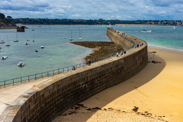 Urlaub in der Bretagne, Frankreich: Hafenstadt Saint-Malo - die dicke, mächtige Hafenmauer an der Altstadt mit Touristen darauf - obrazy, fototapety, plakaty