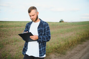Farmer in a plaid shirt controlled his field and writing notes.