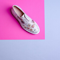 Glamorous silver fish scale patterned woman's shoe, decorated with a multi-colored rhinestone floral ornament on a graphic pink-gray background with copy space. Footwear sales advertising campaign.