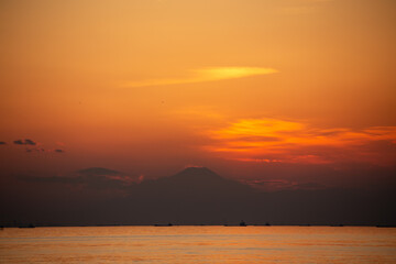 夕焼けに照らされた富士山のシルエットと東京湾と船舶