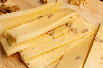 Sliced piece of milk cheese with walnuts