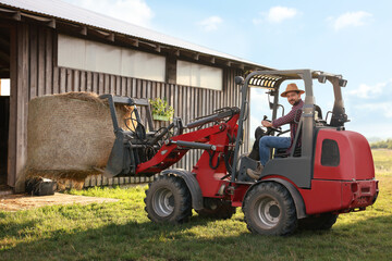 Farmer in loader transporting hay on farm. Agriculture equipment