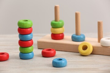 Educational toy for motor skills development. Stacking and counting game pieces on light wooden table