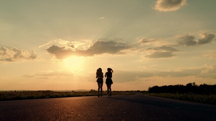 Girls are training, running along road, teamwork of athletes. Slow motion. Athletic young women running along an asphalt road at sunset, teamwork, healthy fitness lifestyle. People run in sun together