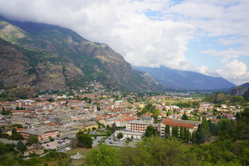Fototapeta na wymiar La città di Susa nelle Alpi italiane nella vallata della Valsusa in una giornata con molte nuvole e sprazzi di sole