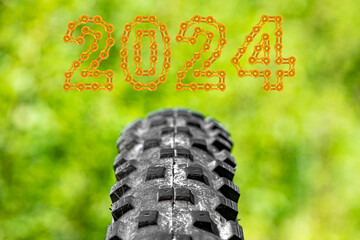 Bicycle off-road rubber tread close-up with 2024 Happy New Year on green nature background