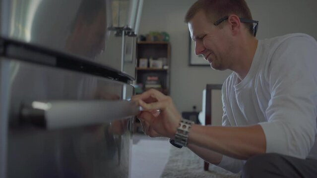 Worker change handle of fridge in kitchen. Applince repair