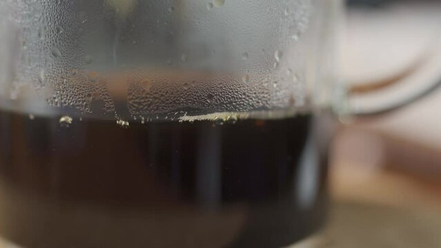 Black coffee dropping into a glass jug