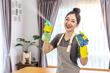 Happy young housewife mistress female in yellow protective rubber gloves with spray and rag,cleaning house, enjoying housework, Asian maid committed to maintaining the highest standards of cleanliness