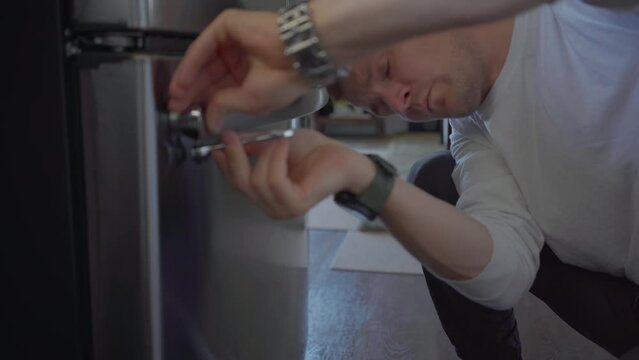 Worker change handle of fridge in kitchen. Applince repair