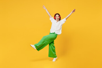 Fototapeta na wymiar Full body young caucasian happy woman she wear white shirt casual clothes listen to music in headphones raise up hands look aside isolated on plain yellow background studio portrait Lifestyle concept