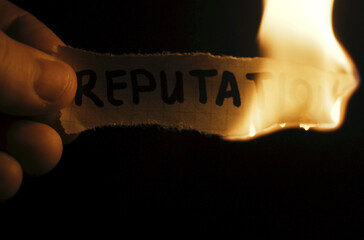 A man burns paper with the inscription - Reputation