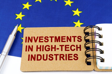 On the flag of the European Union lies a pen and a notepad with the inscription - investments in high-tech industries