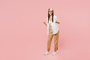 Full body young latin woman she wear white shirt casual clothes sunglasses do winner gesture celebrate clenching fists say yes isolated on plain pastel light pink background studio. Lifestyle concept,