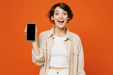 Young fun happy woman she wearing beige shirt casual clothes hold in hand use blank screen...