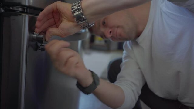 Worker change handle of fridge in kitchen. Applince repair