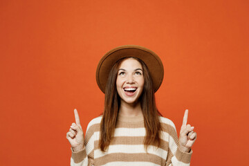 Young woman wear striped sweater hat casual clothes point index finger overhead on area indicate...