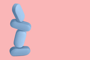 Blue capsules, pills and tablets flying up. On a pink background.