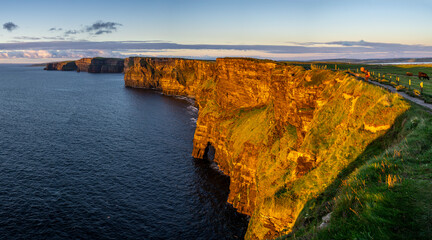 Cliffs of Moher, hiking woman watching the sunset, The Burren, County Clare, Ireland, United...