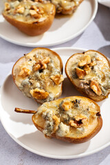 Baked pears with blue cheese, walnuts and honey on white plate closeup, perfect summer dish made of local fruits and affordable products, top view