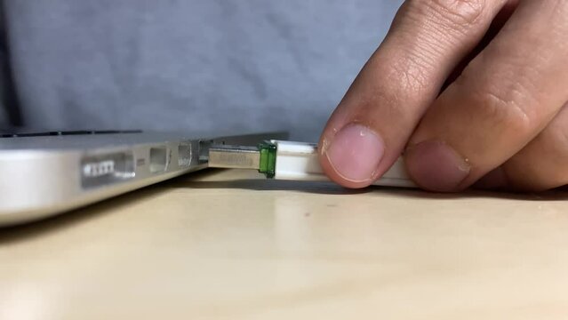 Male hand inserting USB memory storage into slot socket notebook on wooden desk close up view indoor. Transferring photo and date. Technology concept. Happy man banging fist with success emotion.