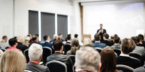 Speaker giving a talk in conference hall at business event. Rear view of unrecognizable people in...