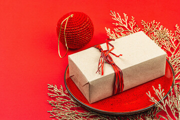 Christmas table setting with a festive gift box in red and gold colors. New Year background