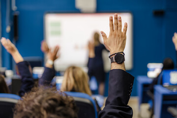 Students raising hands to answer professors question
