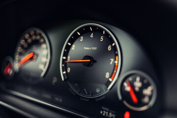 Sports car tachometer and dashboard with backlight. Close-up view of the modern car dashboard. Arrow of speedometer of supercar  - obrazy, fototapety, plakaty