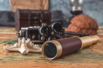 Spyglass and a starfish lie on an old map against the background of a vintage film camera with cassettes. Close-up