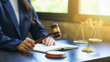 Woman judge hand holding gavel to bang on sounding block in the courtroom.