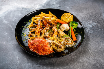 Seafood mixed grill platter with shrimp, prawn, crab, french fries with salad and lime served in dish isolated on background top view of arabic food