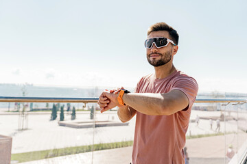 Uses a fitness watch man smiles exercise fitness for health.  Psychological therapy. The runner is a confident man, interval training. The athlete is happy in sportswear jogging.