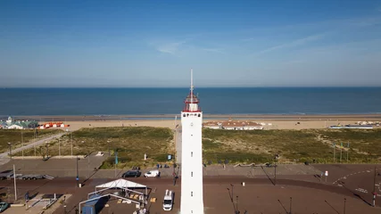 Foto auf Acrylglas lighthouse in Noordwijk Aan Zee protecting vessels in the North Sea on a sunnny summer day. Leuchtturm tower overseas blue skies and calm water © drew