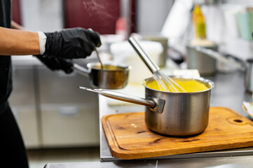 Chef hands cooking cheese sauce in the restaurant kitchen