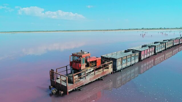 Aerial of an old train standing on the railway in salt lake Bursol. Salt mining at pink lake in Altai region of Russia