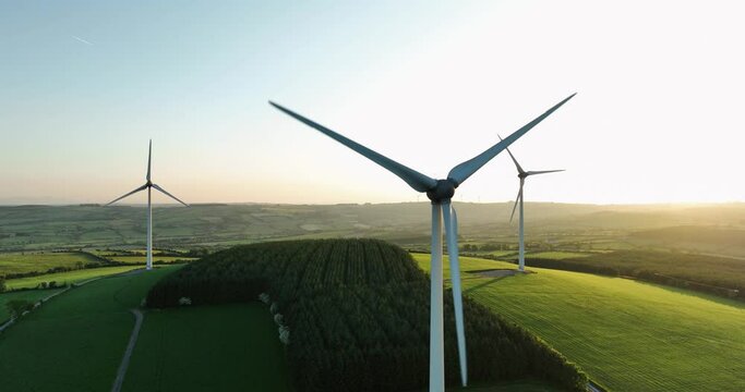 4K Large wind turbines against blue sky at sunset in summer