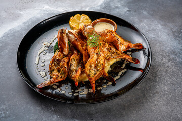 Grilled prawns with dip and lemon slice served in dish isolated on background top view of seafood grill